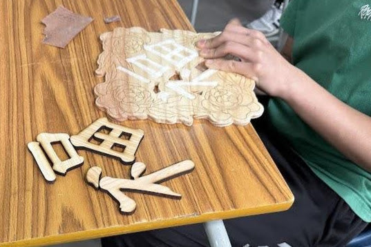 創作過程：學員正在為木製「福」字裝飾的組件打磨或上色